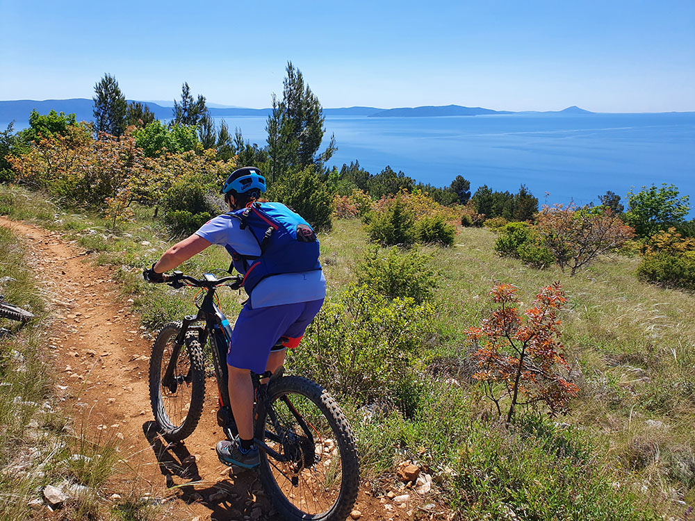 Mountainbiker am Trail mit Meerblick